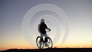 Cyclist on mountain bike rides at sunrise