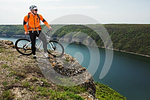 Cyclist in Orange Wear Riding the Bike above River