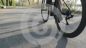 Cyclist pedaling on bicycle back follow shot. Bicycle wheel spinning. Road cycling in the city park. Slow motion