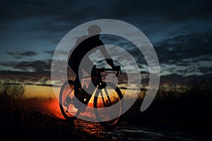 Cyclist pedaling through the fading light, relishing a nighttime ride