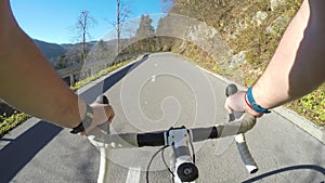 Cyclist POV. Male road cyclist riding his bicycle uphill on a asphalt road on a sunny day