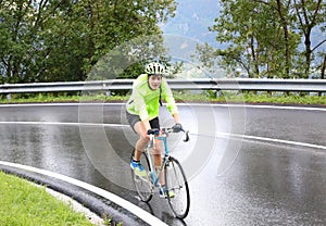 Cyclist with protective helmet pedaling laboriously on the road