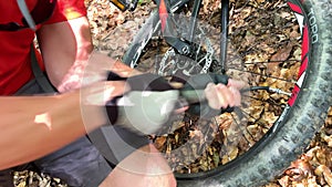 Cyclist pumping bicycle wheel outdoors.