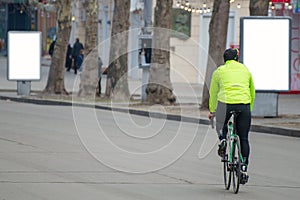 Cyclist on a racing bike outdoors in the city. Two advertising citylights with clear ad place