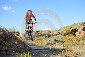 Cyclist in Red Jacket Riding Mountain Bike on the Beautiful Spring Rocky Trail. Extreme Sport Concept