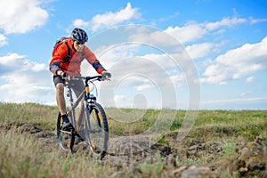 Cyclist in Red Jacket Riding Mountain Bike on the Beautiful Spring Rocky Trail. Extreme Sport Concept