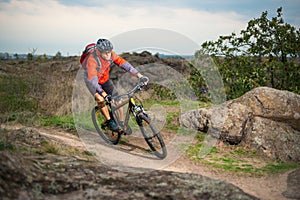 Cyclist in Red Riding the Bike on Autumn Rocky Trail. Extreme Sport and Enduro Biking Concept.