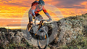 Cyclist in Red Riding the Bike on Autumn Rocky Trail at Sunset. Extreme Sport and Enduro Biking Concept.