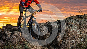 Cyclist in Red Riding the Bike on Autumn Rocky Trail at Sunset. Extreme Sport and Enduro Biking Concept.