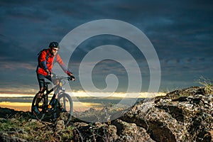 Cyclist in Red Riding the Bike on Autumn Rocky Trail at Sunset. Extreme Sport and Enduro Biking Concept.