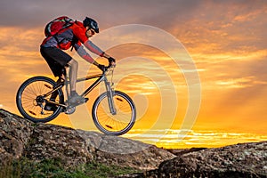 Cyclist in Red Riding the Bike on Autumn Rocky Trail at Sunset. Extreme Sport and Enduro Biking Concept.