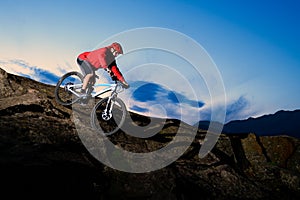 Cyclist in Red Riding the Bike on Autumn Rocky Trail at Sunset. Extreme Sport and Enduro Biking Concept