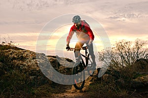 Cyclist in Red Riding Bike on the Autumn Rocky Trail at Sunset. Extreme Sport and Enduro Biking Concept.