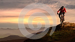 Cyclist in Red Riding Bike on the Autumn Rocky Trail at Sunset. Extreme Sport and Enduro Biking Concept.