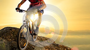 Cyclist in Red Riding the Bike Down the Rock at Sunrise. Extreme Sport and Enduro Biking Concept.