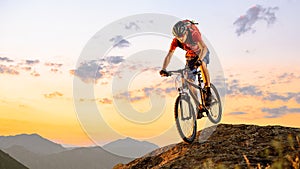 Cyclist in Red Riding the Bike Down the Rock at Sunset. Extreme Sport and Enduro Biking Concept.