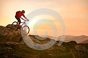 Cyclist in Red Riding Bike on the Summer Rocky Trail at Sunset. Extreme Sport and Enduro Biking Concept.