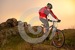 Cyclist in Red Riding Bike on the Spring Rocky Trail at Sunset. Extreme Sport and Enduro Biking Concept.