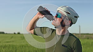 Cyclist restoring fluid balance with water in sports bottle