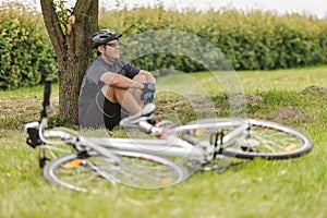 Cyclist rests on a meadow under a tree