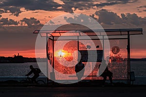 A cyclist rides past a bus stop at sunset