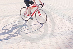 Cyclist rides a red bicycle on a pavement on a city square. Contemporary concept