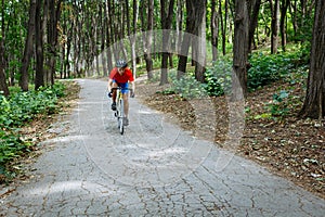 A cyclist rides on a road bicycle on road in woods.