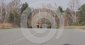 Cyclist rides uphill on bike. Woman pedaling on bicycle outdoor. Female triathlete cycling and training hard. Girl in helmet ridin