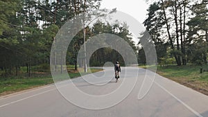 Cyclist riding alone in the park while training for race. Back follow shot of cyclist pedaling road bicycle.