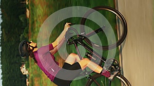 Cyclist riding bicycle at sunset. Female cycling in park. Vertical concept