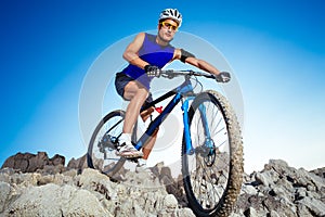 Cyclist Riding the Bike Down Hill on the Mountain Rock