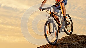 Cyclist Riding the Bike Down the Rock at Sunset. Extreme Sport and Enduro Biking Concept.