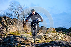 Cyclist Riding the Bike on the Rocky Trail at Sunset. Extreme Sport Concept. Space for Text.