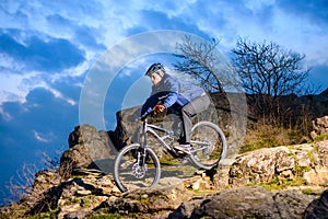 Cyclist Riding the Bike on the Rocky Trail at Sunset. Extreme Sport Concept. Space for Text.
