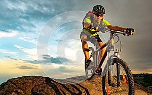 Cyclist Riding the Bike on Rocky Trail at Sunset. Extreme Sport and Enduro Biking Concept.