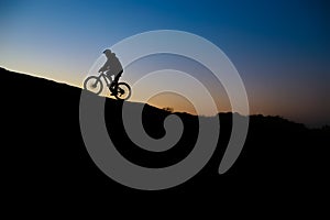 Cyclist Riding the Bike on Rocky Trail at Sunset. Extreme Sport and Enduro Biking Concept.