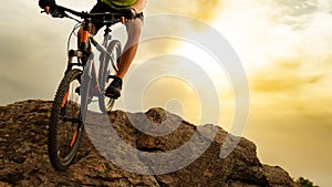 Cyclist Riding the Mountain Bike Down the Rock at Sunset. Extreme Sport and Enduro Biking Concept.