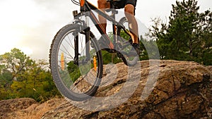 Cyclist Riding the Mountain Bike Down the Rock at Sunset. Extreme Sport and Enduro Biking Concept.