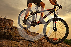 Cyclist Riding the Mountain Bike Down the Rock at Sunset. Extreme Sport and Enduro Biking Concept.