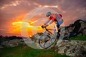 Cyclist Riding Mountain Bike Down Spring Rocky Hill at Beautiful Sunset. Extreme Sports and Adventure Concept.