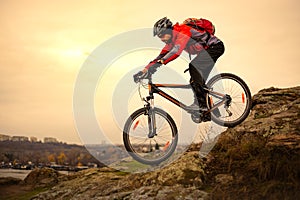 Cyclist Riding the Mountain Bike on the Rocky Trail at Cold Autumn Evening. Extreme Sport and Enduro Cycling Concept.