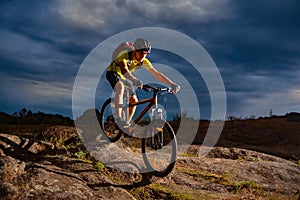 Cyclist Riding the Mountain Bike on Rocky Trail in the Evening. Extreme Sport and Enduro Biking Concept.