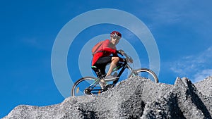Cyclist riding mountain bike on the rocky trail at sunset. Extreme mountain bike sport athlete man riding outdoors lifestyle trail