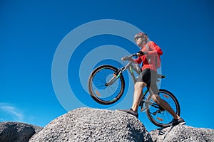 Cyclist riding mountain bike on the rocky trail at sunset, Extreme mountain bike sport athlete man riding outdoors lifestyle trail