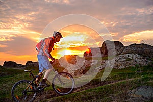 Cyclist Riding Mountain Bike on the Spring Rocky Trail at Beautiful Sunset. Extreme Sports and Adventure Concept.