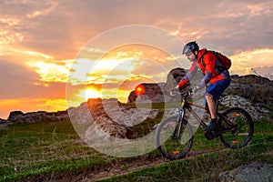 Cyclist Riding Mountain Bike on the Spring Rocky Trail at Beautiful Sunset. Extreme Sports and Adventure Concept.