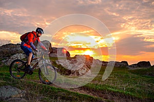 Cyclist Riding Mountain Bike on the Spring Rocky Trail at Beautiful Sunset. Extreme Sports and Adventure Concept.