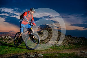 Cyclist Riding Mountain Bike on Spring Rocky Trail at Beautiful Sunset. Extreme Sports and Adventure Concept.