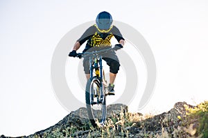 Cyclist Riding the Mountain Bike on the Summer Rocky Trail at the Evening. Extreme Sport and Enduro Cycling Concept.