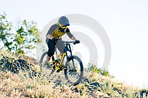 Cyclist Riding the Mountain Bike on the Summer Rocky Trail at the Evening. Extreme Sport and Enduro Cycling Concept.